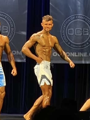 Men's Physique client competing on stage at an OCB competition